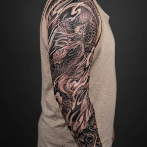 Arm with detailed dragon sleeve tattoo in black and grey.