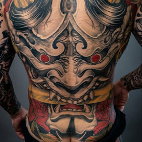 Back tattoo of a traditional Japanese oni mask with red eyes.