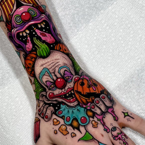 Colorful clown and pumpkin tattoo on the back of a hand.