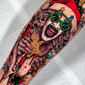 Horror Santa tattoo holding a gingerbread man, wrapped in Christmas lights.