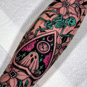 Ouija board tattoo with a skeleton, ghost and flowers.