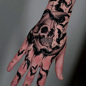 Black and grey skull tattoo on the back of a hand.