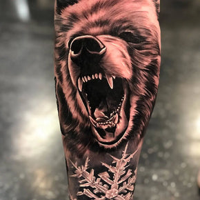 Tattoo of a roaring bear with detailed fur and fangs.
