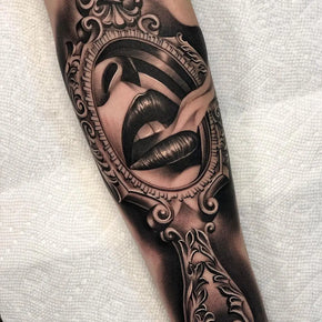 Tattoo of ornate mirror reflecting lips and tongue design.