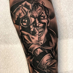 Tattoo of a grinning character in a hat holding a camera.