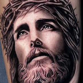 Tattoo of Jesus with a crown of thorns looking upward.
