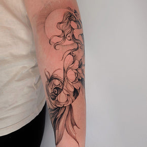 Ornate black and grey tattoo of a koi fish and floral designs on a person's forearm.