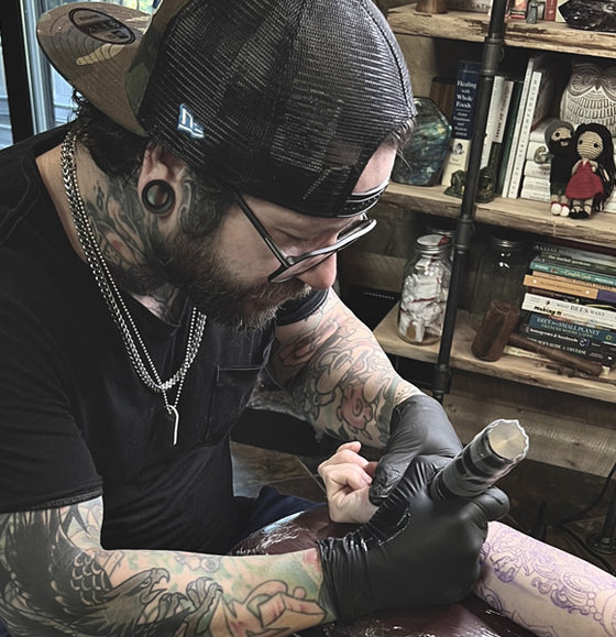 Tattoo artist working on a client's arm.