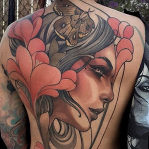 Tattoo of a woman's face with flowers and a moth on her back.