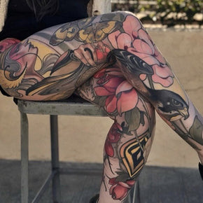 Colourful tattoo sleeve on legs featuring flowers and abstract designs.