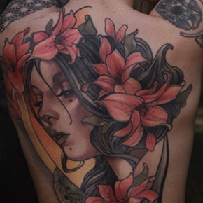 Tattoo of a woman's face with flowing hair and red flowers.