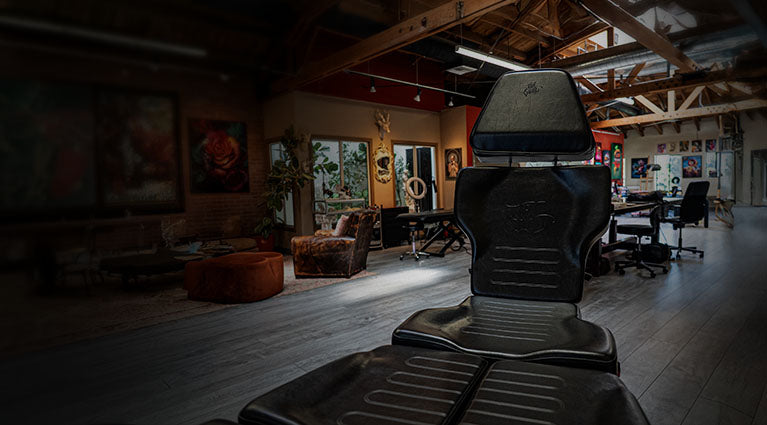 Tattoo studio with a black reclining chair in the foreground.