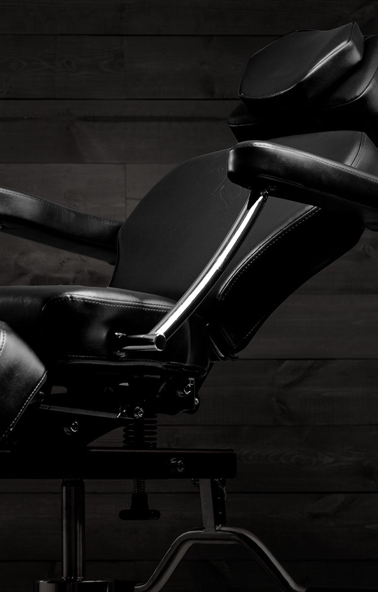 Black TATSoul client chair against a dark wood wall.