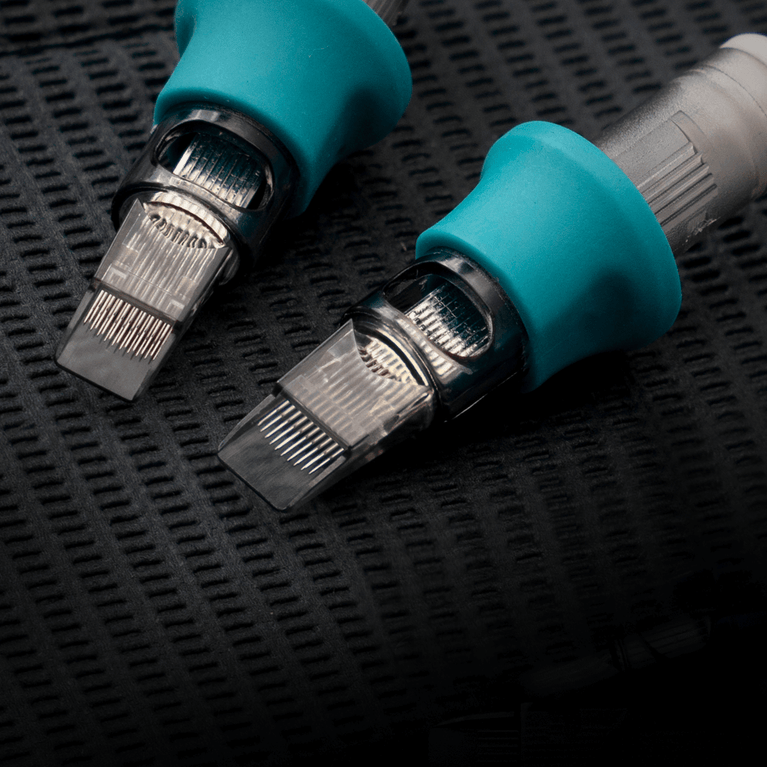 Tattoo needle cartridges with blue grips, close-up view.