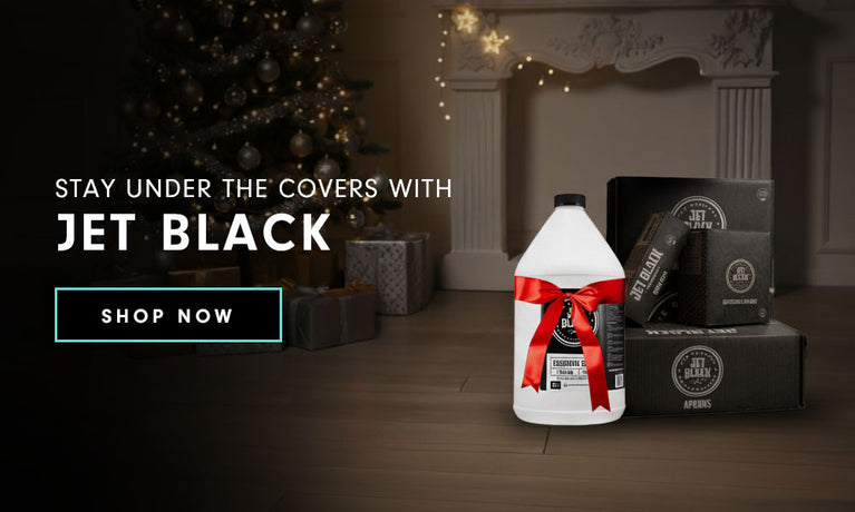 Bottle with red bow next to Jet Black product boxes and a 
