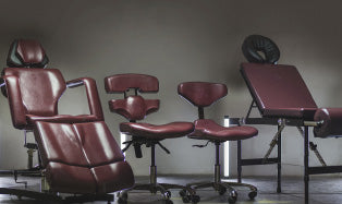 Tattoo studio chairs and stools in dark red leather.
