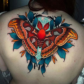 Back tattoo of a large, colourful moth surrounded by blue leaves.