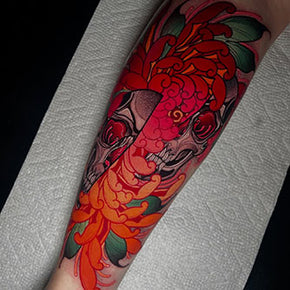 Tattoo of vibrant orange flowers intertwined with a detailed skull design on an arm.