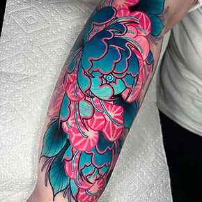 Floral tattoo with vibrant blue and pink hues on forearm.