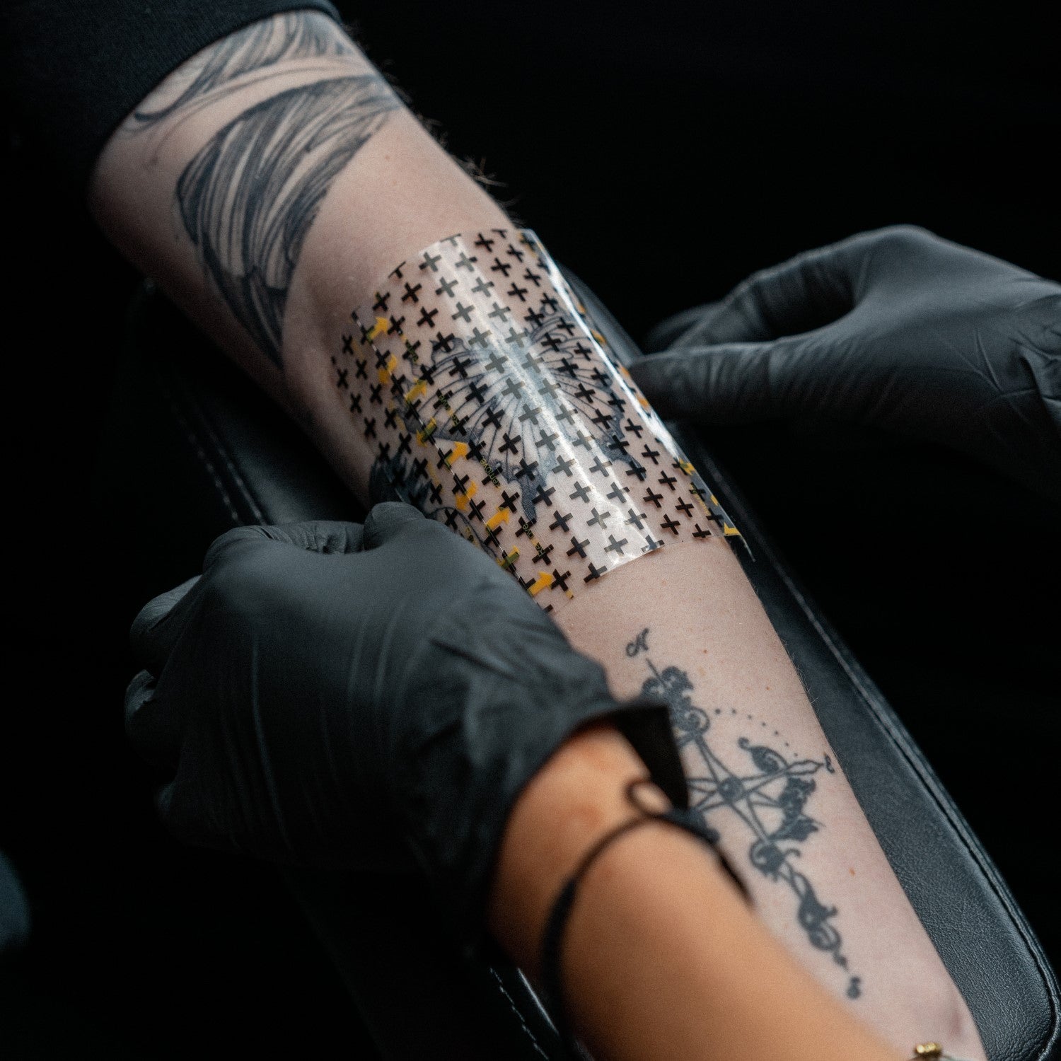Tattoo artist applying a Recovery Derm Tattoo Shield bandage on a new tattoo