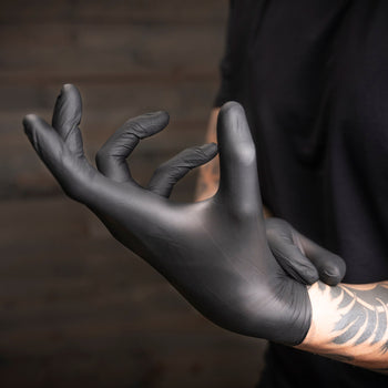 A person wearing black disposable gloves, adjusting the fit.
